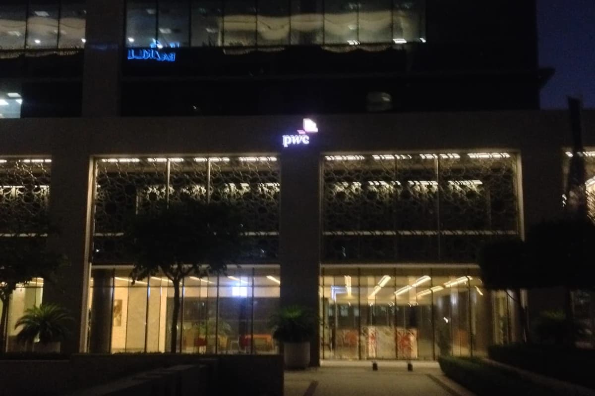Ночной вид офиса PwC в Emaar Square в Дубае с подсвеченным логотипом компании.