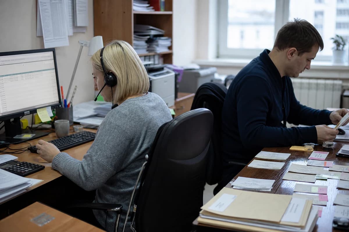 Два сотрудника обрабатывают долговые дела за соседними рабочими столами.