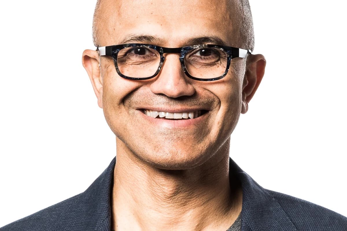 Портрет генерального директора Microsoft Сатьи Наделлы в очках на светлом фоне.