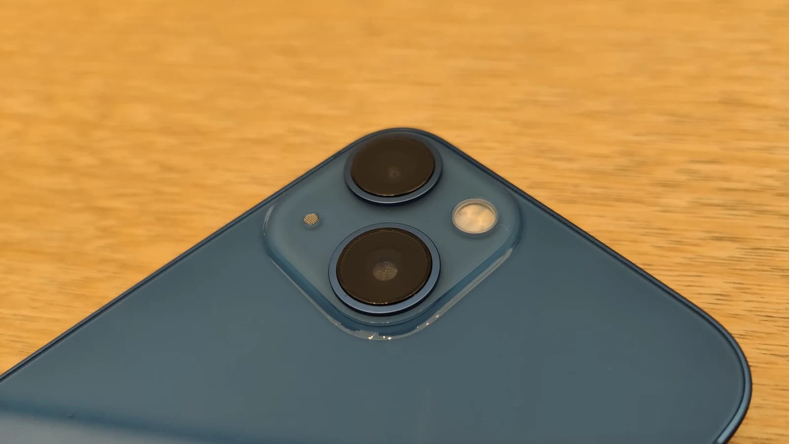Крупный план блока из трёх камер и вспышки на задней панели iPhone 13.