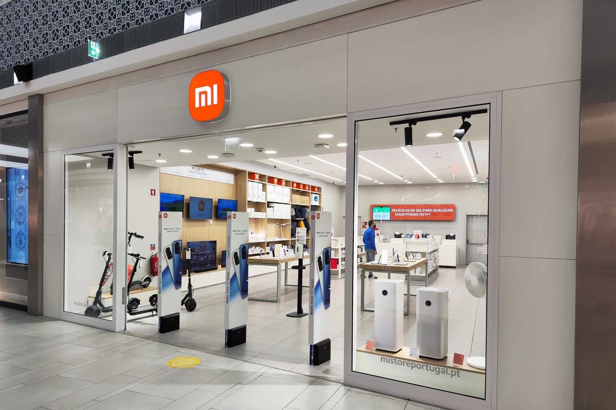 Вход в светлый магазин Xiaomi с фирменной оранжевой вывеской и витринами электроники
