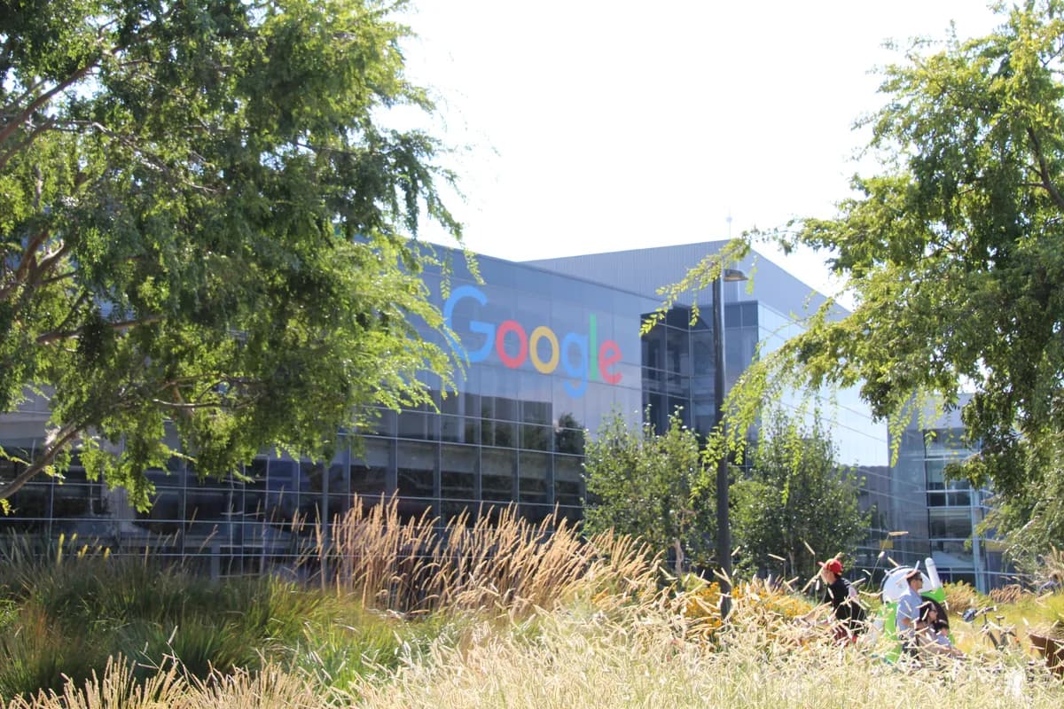 Цветная вывеска Google на фасаде офисного здания среди деревьев