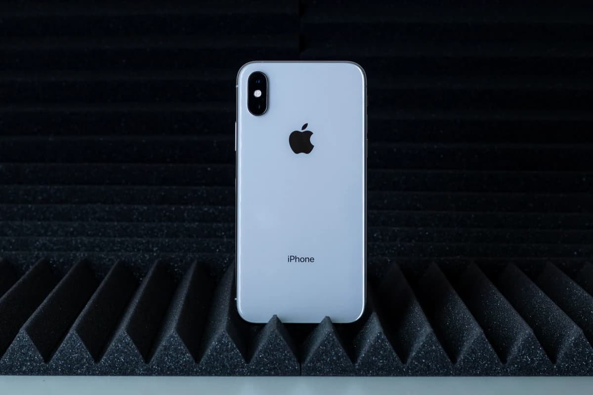 Серебристый iPhone, снятый сзади на фоне чёрного акустического поролона