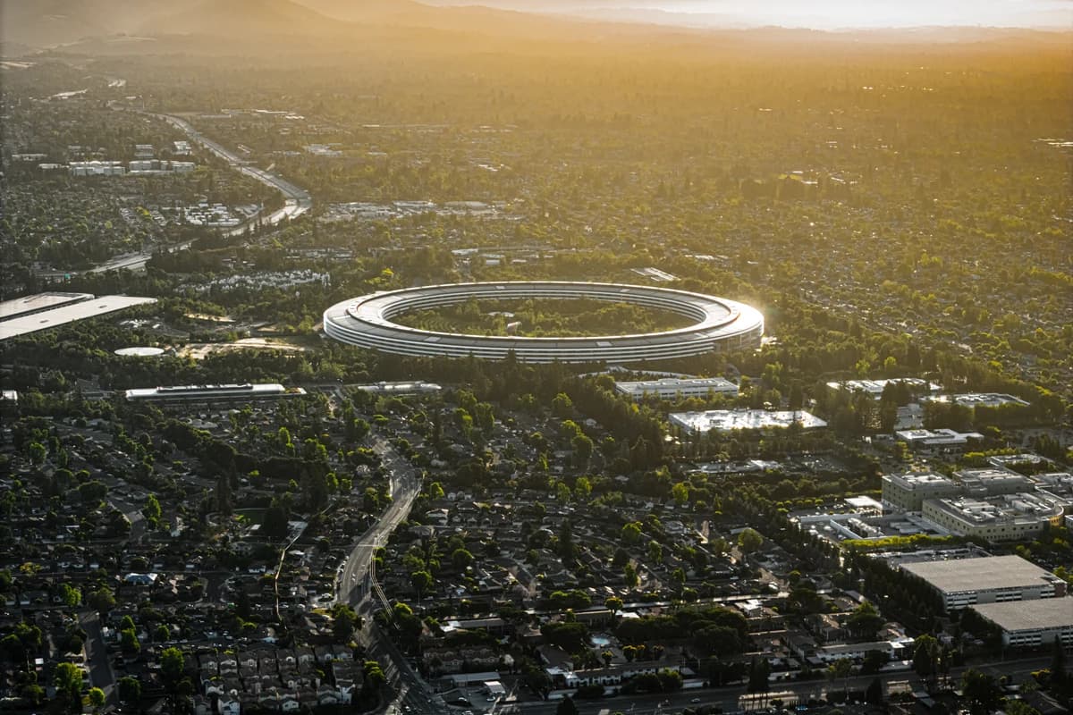 Аэрофотоснимок кольцевого здания Apple Park на фоне городской застройки и холмов