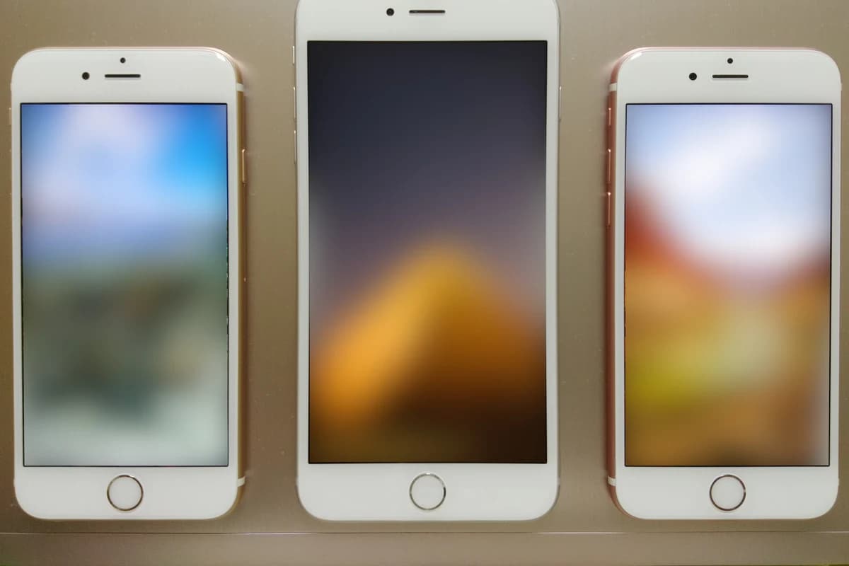 Три белых смартфона Apple с размытыми изображениями на экранах
