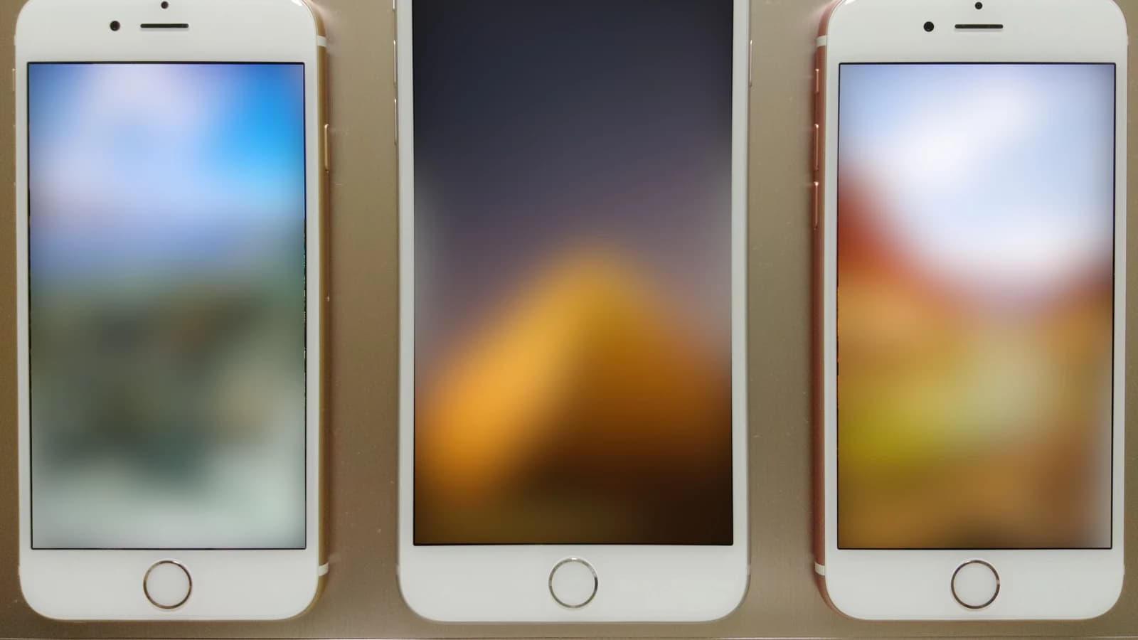 Три белых смартфона Apple с размытыми изображениями на экранах