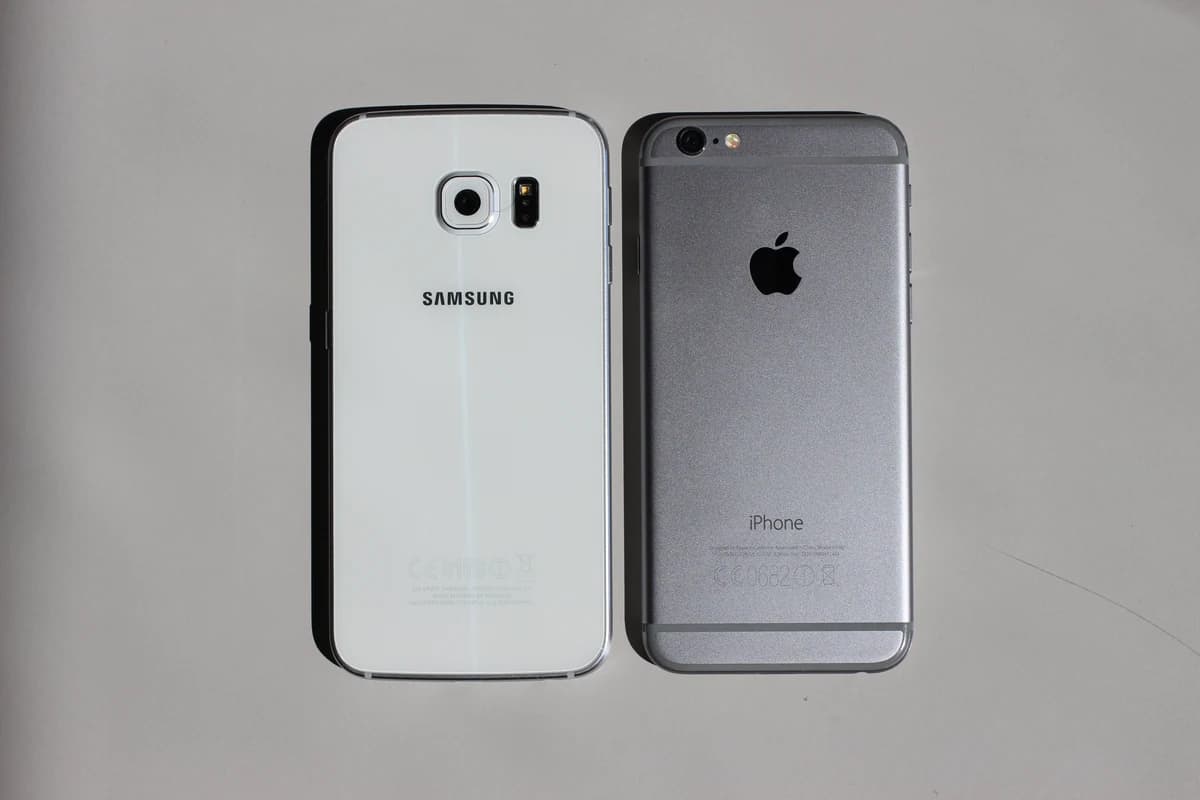 Смартфоны Samsung и Apple iPhone лежат рядом задними панелями вверх
