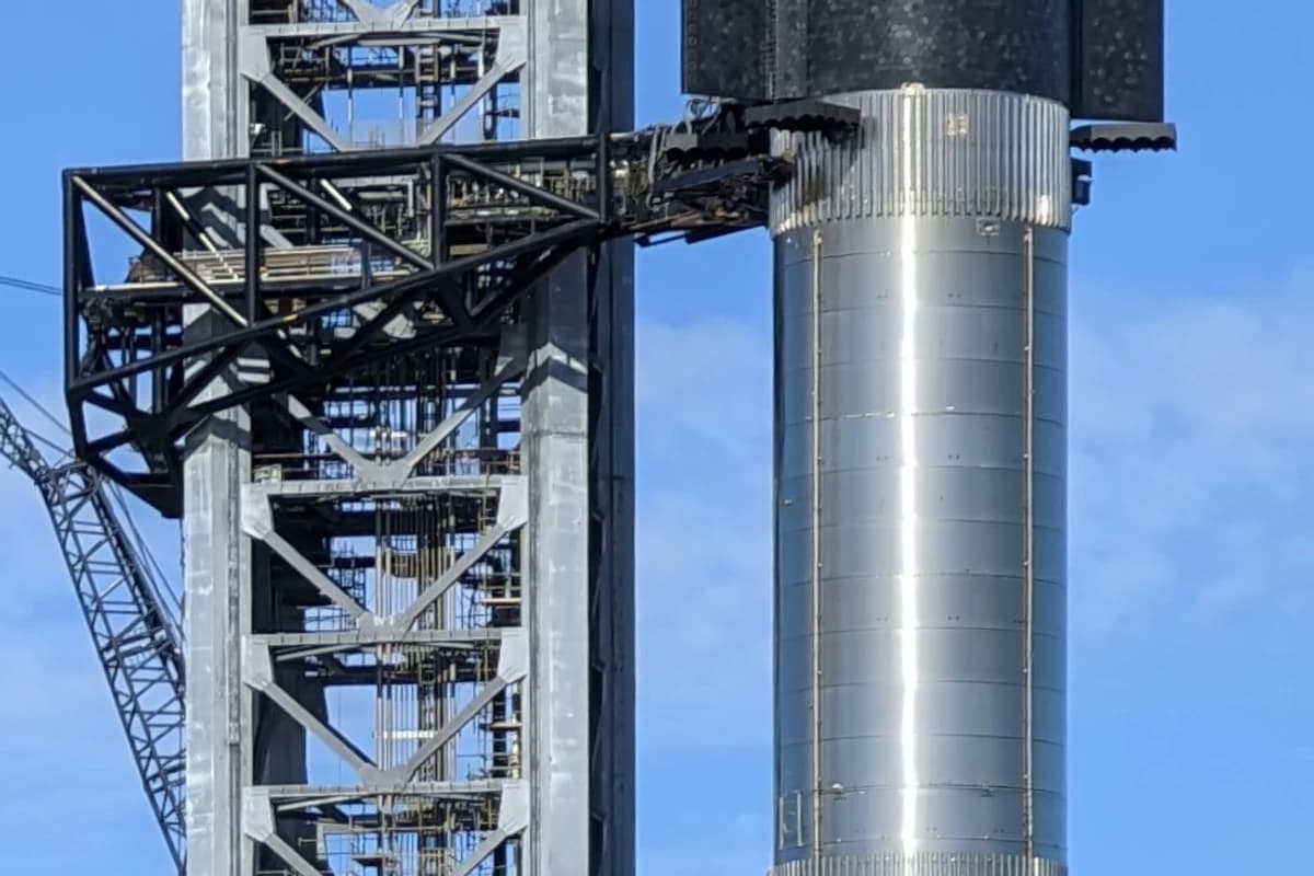 Космический корабль Starship на ускорителе Super Heavy рядом с башней обслуживания