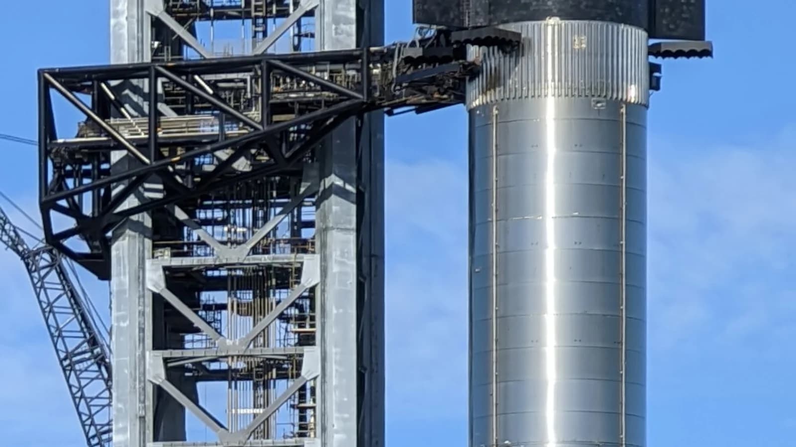 Космический корабль Starship на ускорителе Super Heavy рядом с башней обслуживания