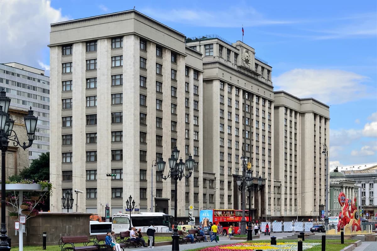 Монументальное административное здание с российским флагом на крыше у городского сквера