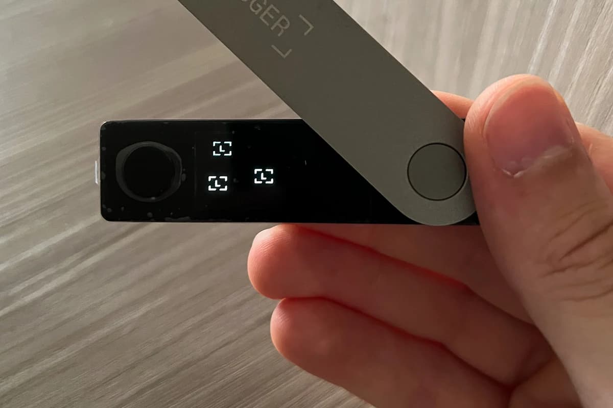 Аппаратный криптокошелёк Ledger в руке крупным планом