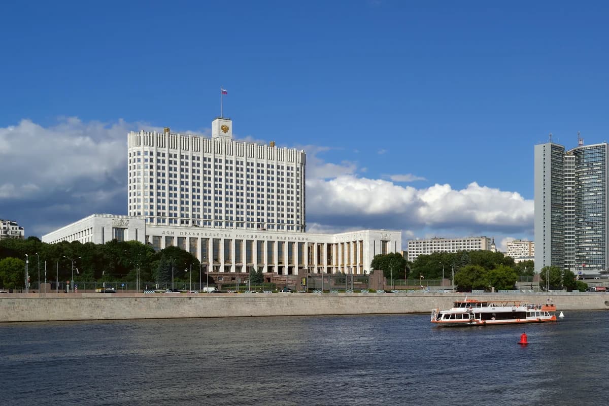 Белое административное здание с российским флагом на берегу реки