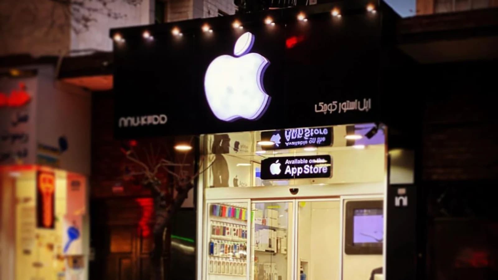 Освещённая витрина магазина с крупным логотипом Apple