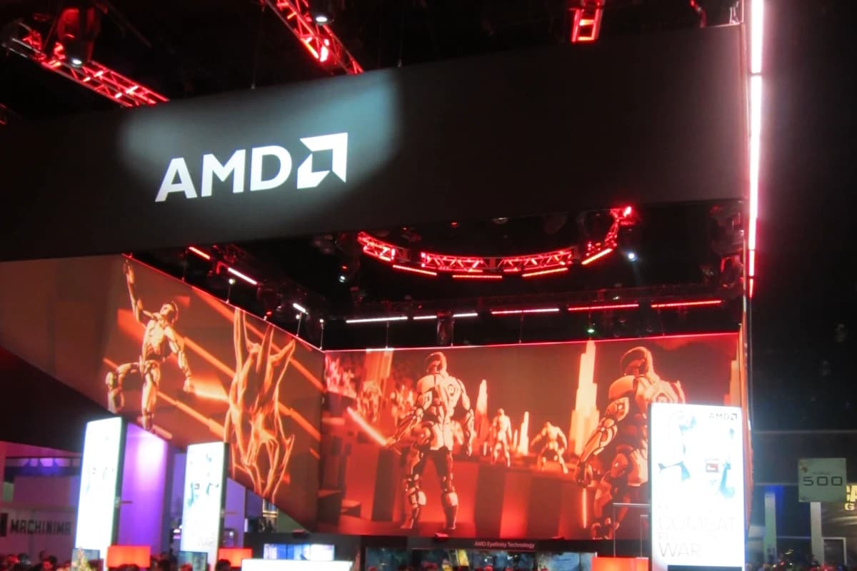 Выставочный стенд AMD с логотипом, экранами и толпой посетителей