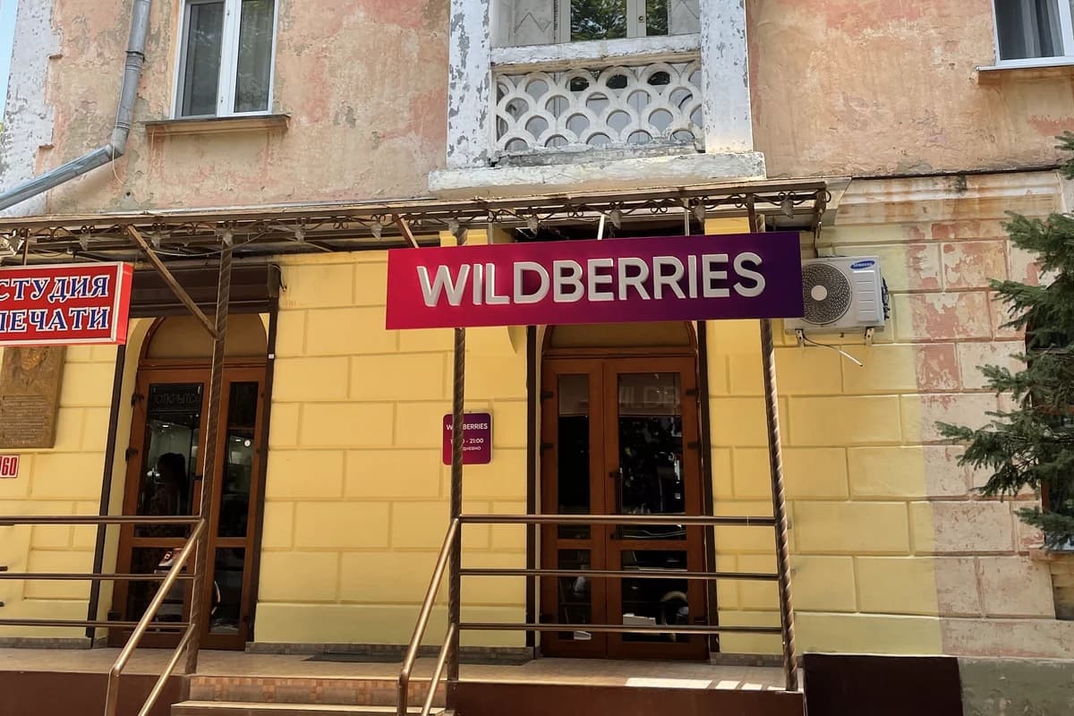 Вход в пункт выдачи Wildberries с фирменной вывеской на фасаде жилого дома