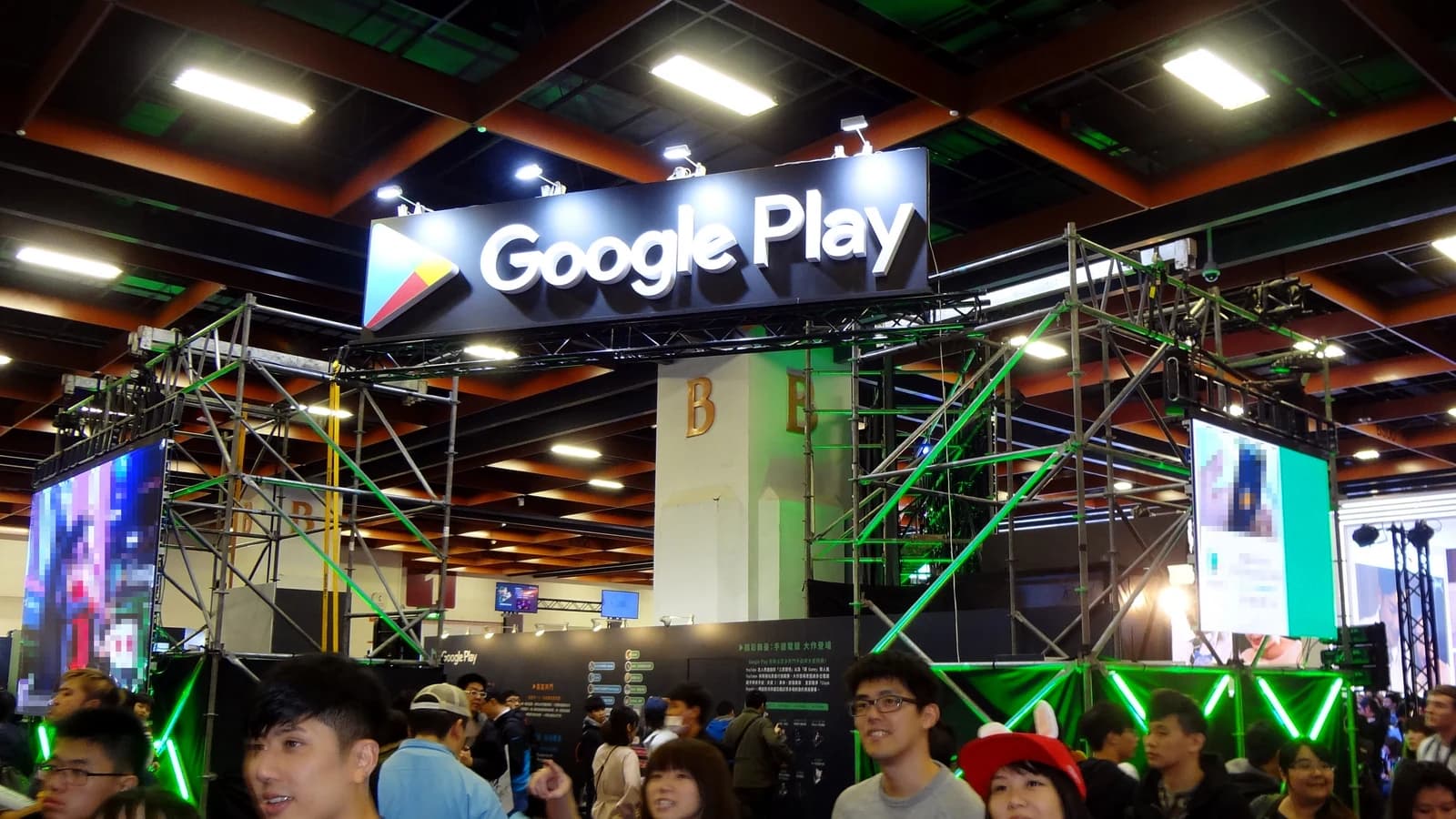 Вывеска Google Play над выставочным стендом с посетителями