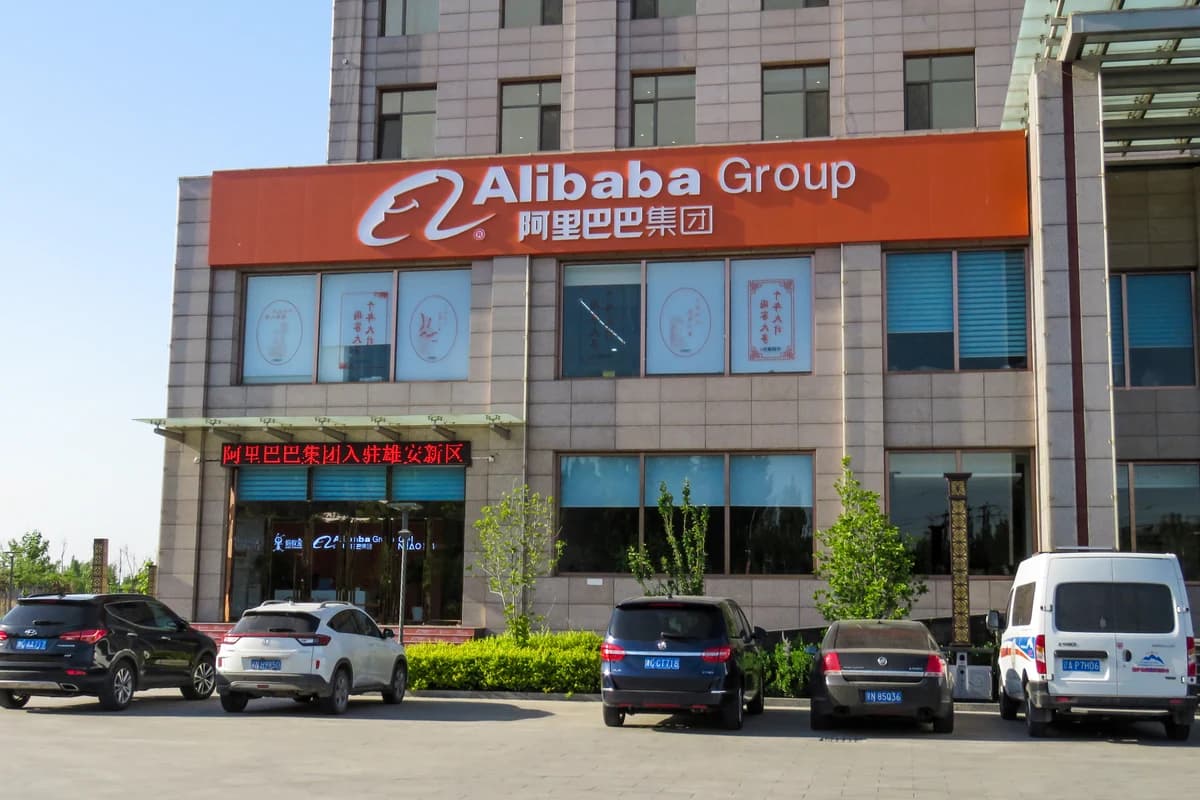 Фасад офисного здания с крупной вывеской Alibaba Group и припаркованными автомобилями