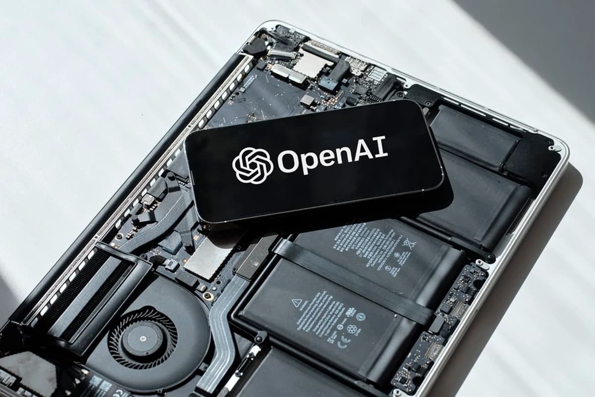 Смартфон с логотипом OpenAI лежит на разобранном ноутбуке