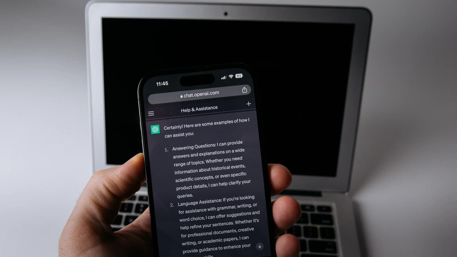 Смартфон с открытым интерфейсом ChatGPT на фоне ноутбука