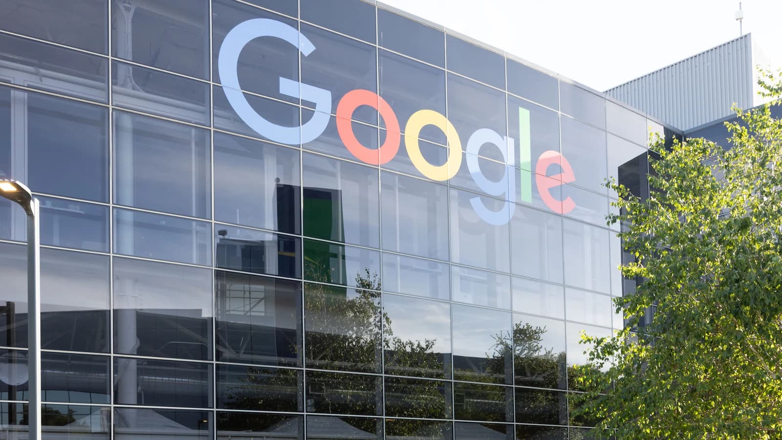 Группа людей перед офисным зданием с крупной вывеской Google
